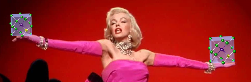 A still of Marilyn Monroe from the "Diamond's Are a Girl's Best Friend" performance, holding an illustration of a nitrogen vacancy center in each outstretched hand.